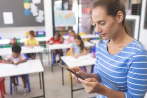 schoolteacher-using-digital-tablet-at-school-in-cl-4XVZ58D-min